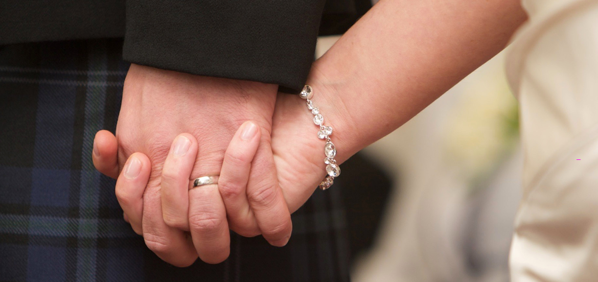 Clasped hands wearing wedding rings